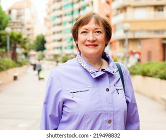 Outdoor Portrait Of Smiling Mature Woman At European Town Street