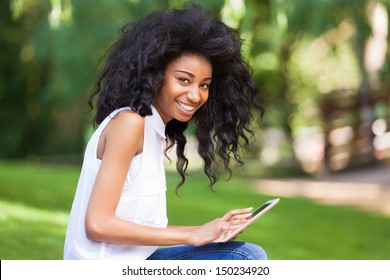 Outdoor Portrait Of A Smiling Teenage Black Girl Using A Tactile Tablet - African People