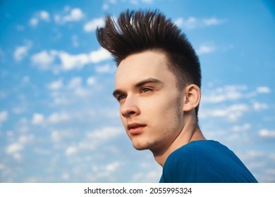 Outdoor Portrait Of Teenager Boy Looking Away With Hair Blowing In The Wind Against Evening Sky