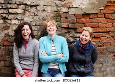 Outdoor portrait of three women standing next to the vintage wall