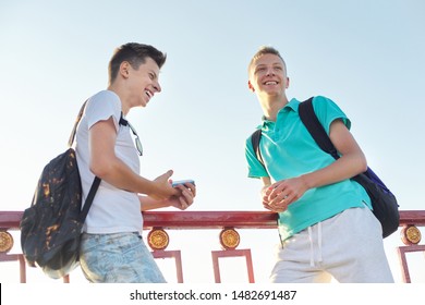 Outdoor Portrait Of Two Talking Boys Teenagers 15, 16 Years Old, Males Laughing Look At Smartphone, Golden Hour