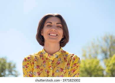 Outdoor Portrait Of Woman In Yellow Summer Dress Looking To Camera With Huge Smile, Blue Sky On Background, Sunny Day, Happy Cheerful Mood