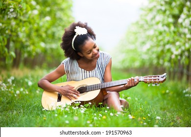 Outdoor Portrait Of A Young Beautiful African American Woman Playing Guitar - Black People