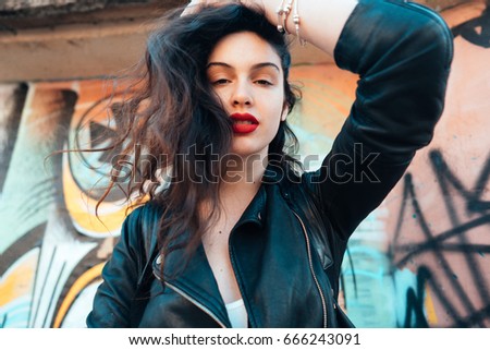 Outdoor portrait of young beautiful fashionable playful lady posing on old street