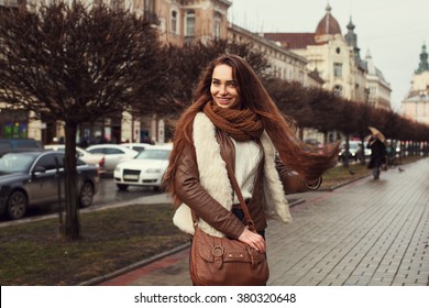 Outdoor portrait of young beautiful smiling lady wearing stylish clothes standing on the street. Model looking at camera. Female fashion concept. 