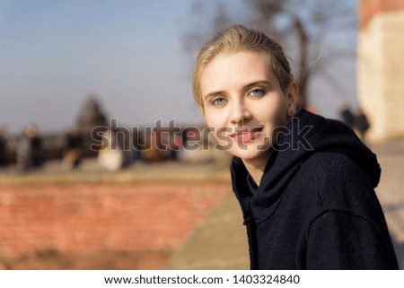 Outdoor portrait of young blonde beautiful woman with red brickwork on background. Photo with copy space