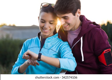 Outdoor Portrait Of Young Couple Using They Smartwatch After Running.