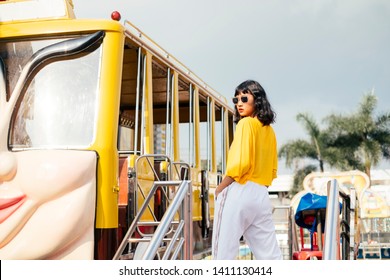 Outdoor Portrait Of Young Fashionable Woman Wearing Yellow Shirt, Turtleneck, Green Corduroy Trousers, Belt, Holding Round Orange Suede Handbag, Posing In Street Of European City. Copy Space For Text