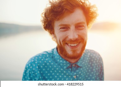 Outdoor portrait of young handsome smiling ginger man with beard - Shutterstock ID 418229515