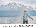 Outdoor portrait of young happy woman enjoying amazing mountain landscape, back view