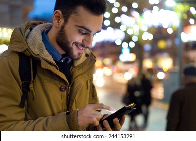 Outdoor portrait of young man using his mobile phone at night.