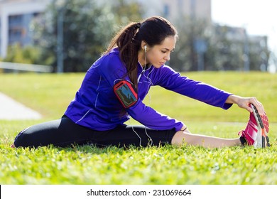 Outdoor portrait of young woman stretching and preparing for running.