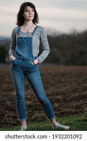 An Outdoor Portrait Of A Young Woman Wearing Dungarees In The Countryside 