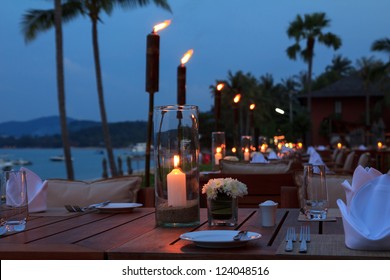 Outdoor restaurant tables, dinner setting on the beach at evening