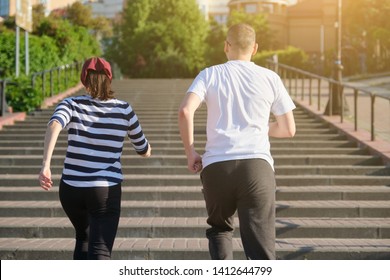 Outdoor Running Mature Couple. Man And Woman Of 40 Years Old Running Upstairs, View From The Back.