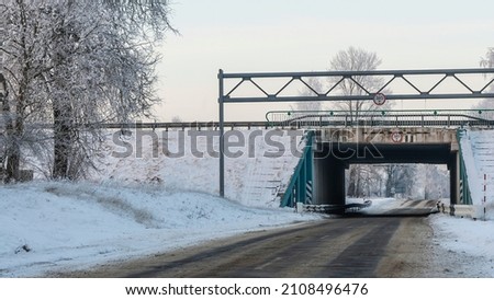Outdoor scenery of empty street pass through small tunnel under highway and agriculture field covered by snow in winter. Space for text.