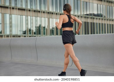 Outdoor shot of active slim woman has jog exercises being physically active covers long distance wants to come first at finish dressed in sportswear has morning workout. Back view of female jogger - Shutterstock ID 2040198851