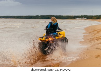 Outdoor Shot Of Happy Couple Ride Quadrocycle On Seashore, Enjoy Speed And Extreme Sport, Have Ride Outside During Summer Time. Woman And Man Riders On ATV. Motocross And Excursion Concept.