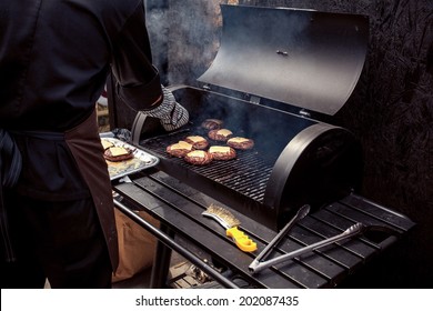 Outdoor shot of man cooking meat for cheeseburger on grill