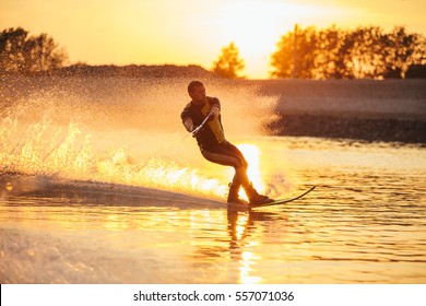 Outdoor shot of man water skiing at sunset . Man wakeboarding on a lake.