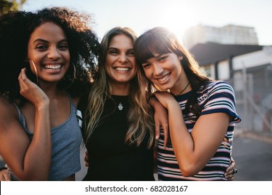 Outdoor shot of three young women having fun on city street. Multiracial female friends enjoying a day around the city.