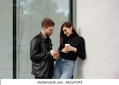 Outdoor Shot Of Young Attractive Woman Flirting With Man, She Gives Number Phone With Shy Smile. Handsome Guy Flirting In The Street With Pretty Girl Exchanging Phone Numbers. Love Dating Concept