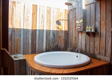 Outdoor Shower With A White Bathtub And Shampoo Cream In The Bathroom Made From Wooden Wall For Tourists To Steep A Shower After The Tour.