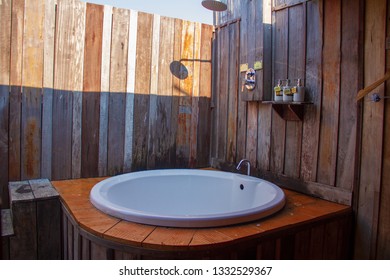 Outdoor Shower With A White Bathtub And Shampoo Cream In The Bathroom Made From Wooden Wall For Tourists To Steep A Shower After The Tour.