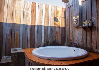 Outdoor Shower With A White Bathtub And Shampoo Cream In The Bathroom Made From Wooden Wall For Tourists To Steep A Shower After The Tour.