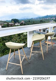 Outdoor Sitting Or Dining Area On Building Rooftop At Batu City With Natural View Of Villages Landscape, 3 Empty Wooden Stool Bar Chair At Outdoor Cafe Terrace To Enjoying The Scenery.