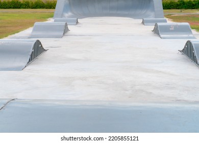 Outdoor Skatepark With Blue Sky And Grey Concrete