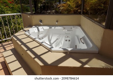 An Outdoor Spa Bath On A Deck With Shadows From The Overhead Lattice And Leaves