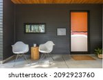 Outdoor space with two chairs and a orange and white front door