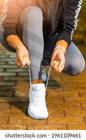 Outdoor Sport Concepts. Active Female Runner Tighten Up Her Shoelaces During Jogging Training Exercise Outdoor. Vertical Image