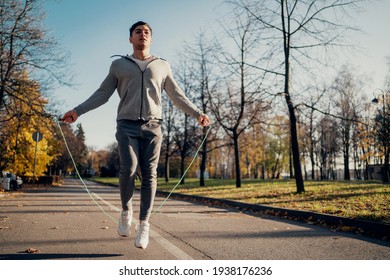 Outdoor sports activities. The development of the cardiac system is a load on the heart. Does exercises on a skipping rope. A young man of Caucasian appearance. Walks in the park in the city center. - Powered by Shutterstock