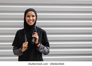 Outdoor Sports. Happy Muslim Lady Wearing Modest Sportswear Posing With Jump Rope, Portrait Of Fit Young Islamic Lady In Hijab Training Outside, Looking At Camera And Smiling, Copy Space - Powered by Shutterstock