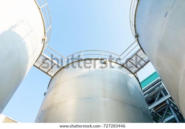 Outdoor steel bulk storage tanks in blue sky\
background, for industrial and\
factory