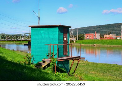 Outdoor Storage Shed On The River Bank. Rustic Entrance Door And Stairway. Nice Turquoise Color On Wall