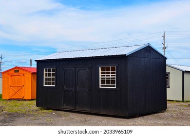 Outdoor Storage Shed, With Symmetrical Design. Black Painted, Wooden Shed And Grey Metallic Rooftop. 