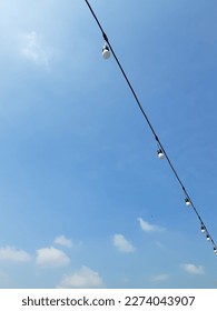 Outdoor string light bulb under the clear blue sky 