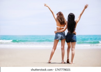 Outdoor Summer Portrait Of The Back Image Of Two Asian Beautiful Girls In A Sexy Bikini Standing On The Beach In Summer. Girls Best Friends. Sexy Buttocks. Concept Vacation,  Holiday In Summer