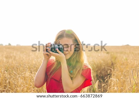 Outdoor summer smiling lifestyle portrait of pretty young woman with camera.