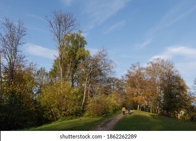 Outdoor Sunny View Of Elder Couple Walk On Small Trail Path Up To Small Hill Surround With Natural Autumn Atmosphere And Leaves.