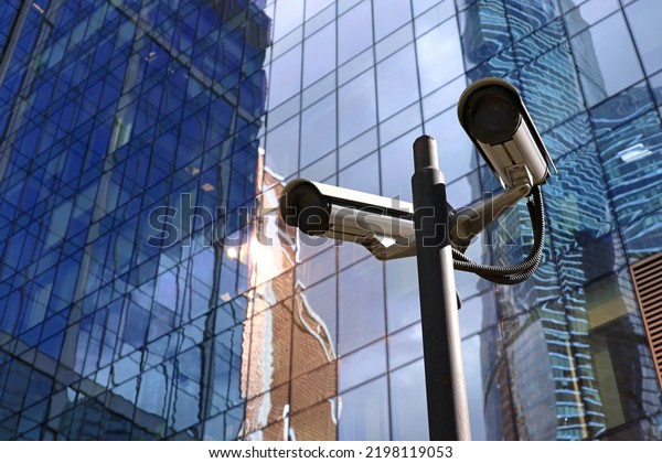 Outdoor surveillance video cameras\
on background of skyscraper tower. Cctv camera near the business\
center, concept of security, privacy and protection from\
crime