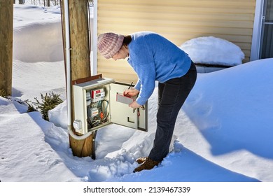 An Outdoor Switchboard With An Electric Meter, Woman Taking Readings.