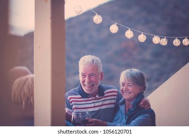 outdoor terrace with golden light and four adult seniors men and woman staying together with joy and happiness drinking wine together - Powered by Shutterstock