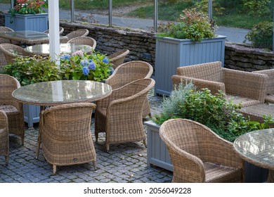 Outdoor Terrace In Hotel Or Restaurant With Wooden Wicker Tables And Chair, Boxes Of Green Plants And No People. Comfortable Summer Garden Or Street Cafe In Woods Or City Park For Relaxing Outside