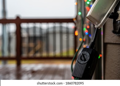 Outdoor Timer And GCFI Outlet With Cover. Blurred Christmas Lights In Background.