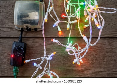 Outdoor Timer And GCFI Outlet With Cover. Blurred Christmas Lights In Background.