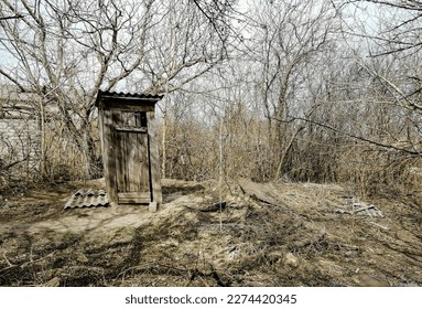 Outdoor toilet. Wooden toilet booth outside. Toilet in the yard of the house. The toilet is falling apart.